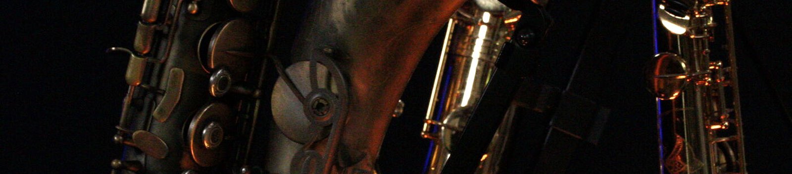 Trois saxophones serrés, cuivre sombre et contre-jour bleu