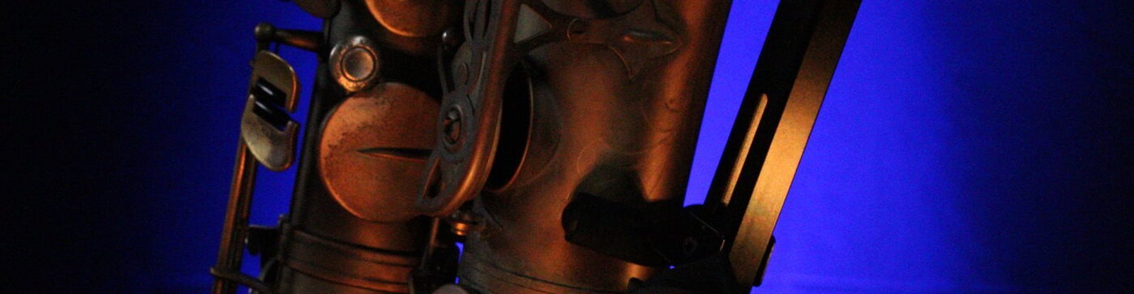 Saxophone body in copper, raking light against deep blue